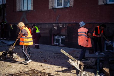 Kharkiv, Ukrayna, 16 Eylül 2025 Temizlik işçileri, Rus Şahin İHA 'sının bir binaya çarptığı sokakta karşılık veriyor. Hasar büyüktü ve bina alev aldı..