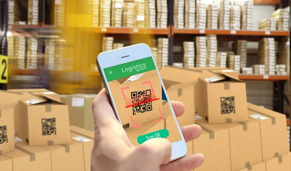 Hand holding Smart phone scanning package QR code at the warehouse, Smart logistic, Industry 4.0, Smart warehouse, Conceptual photo.