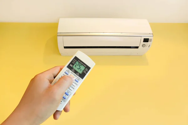 Hand turning on home air conditioning system at 25 degree, energy saving