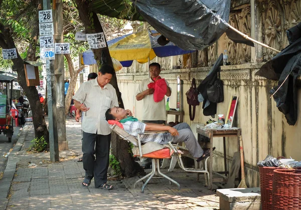 PHNOM PENH, CAMBODIA : Traditional lifestyle of people in Cambodia, Barber work at open air shop on pavement, man cut hair for senior to make living on March 17, 2015