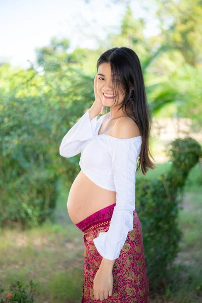 Joven asiática hermosa embarazada mujer en vestido blanco tocando su vientre —  Fotos de Stock