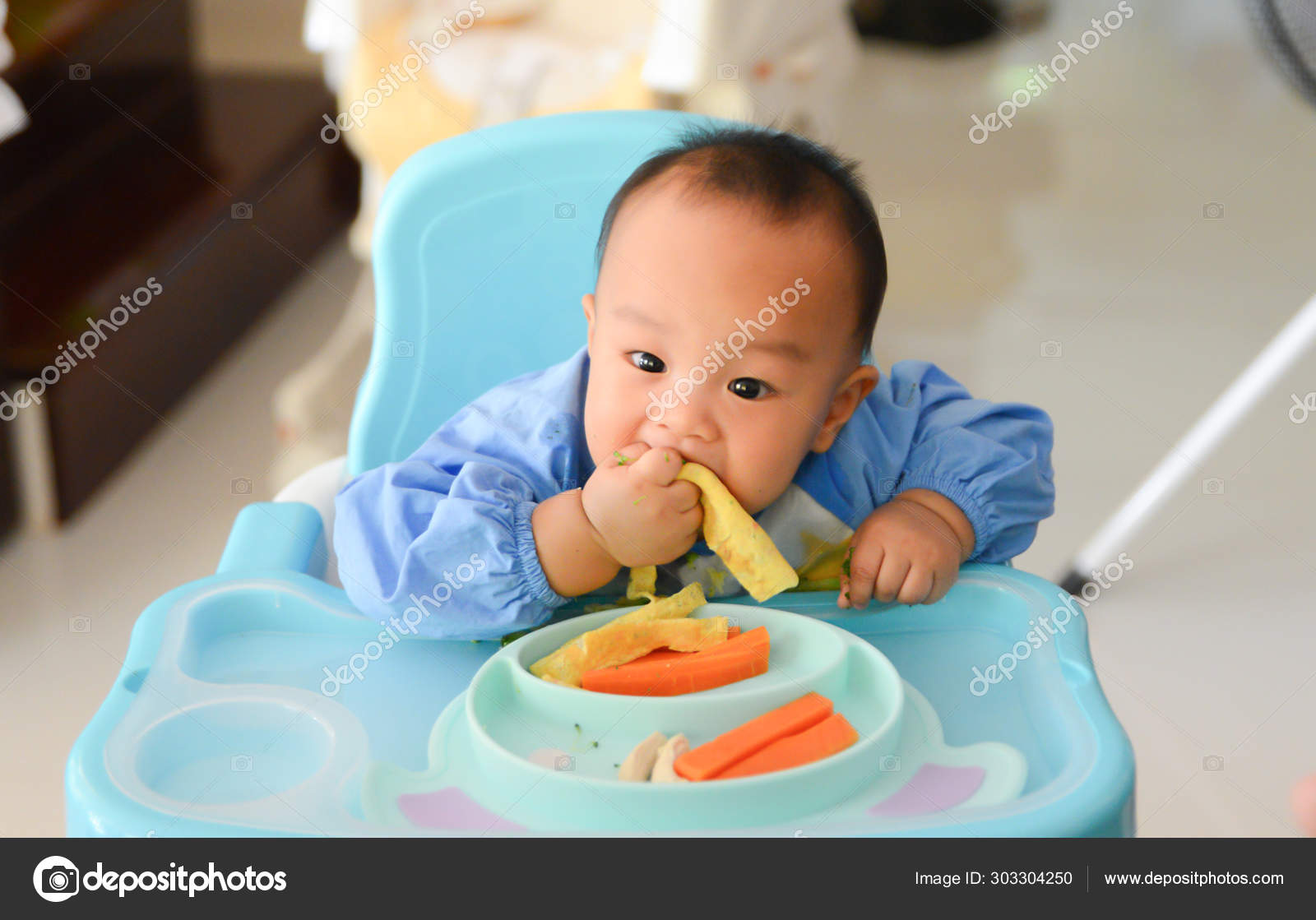 Asian baby boy 6 months old eating with Baby Led Weaning (BLW