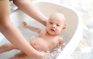 4 aylık Asyalı erkek bebek baba elinde küvette banyo sahip.