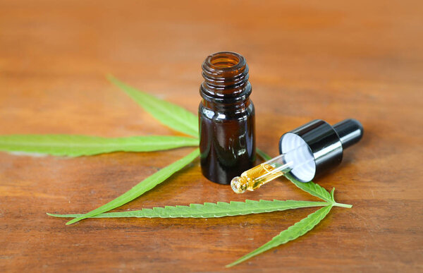 CBD Oil glass bottle with Marijuana background, Cannabis liquid