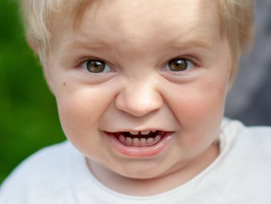 Park arka plan üzerinde yeşil ağaçlar ile duygusal küçük çocuk portre