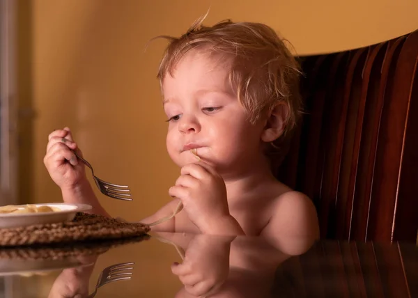 El niño en la cocina en la mesa comiendo macarrones y una vista interesante desde la parte superior — Foto de Stock