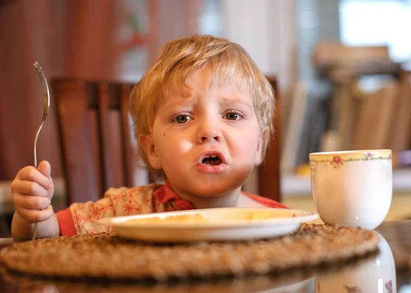 Child in the kitchen eating sausage and mashed potatoes — Stock Photo, Image