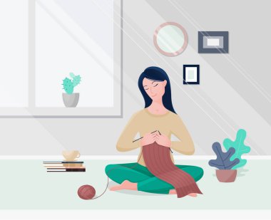 Modern oturma odasında örgü ören genç bir kadın..