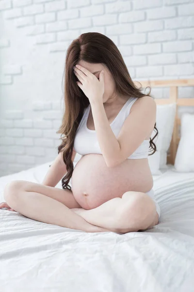 ベッドと感じうつ病の自宅の上に座って妊娠中の女性 — ストック写真