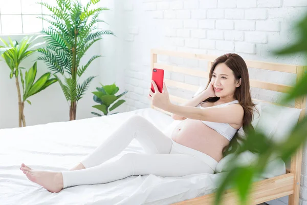 Schwangere Sitzt Auf Bett Und Macht Fröhlich Selfie — Stockfoto