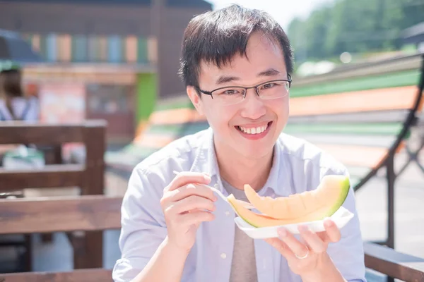happy man eating  cantaloupe and smiling