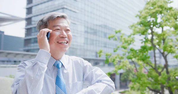 old businessman smiling  happily and speaking on   phone