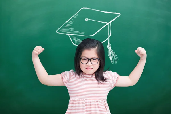 Bonito Menina Mostrando Forte Braços Com Bacharel Cap Quadro Verde — Fotografia de Stock