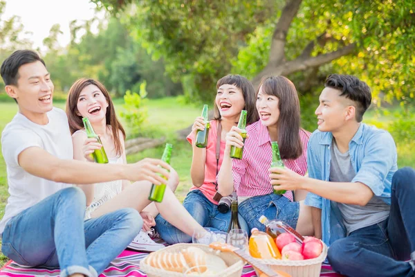 people drinking  beer and smiling  happily  on a picnic