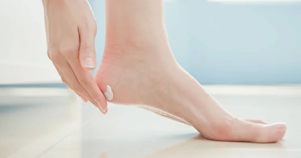 beauty woman applying  cream on  foot at home