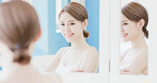 美容女性の鏡で見ていると 自宅にクリームを適用します — ストック写真
