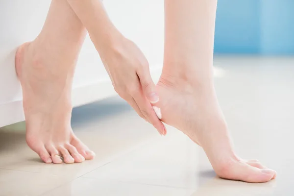 beauty woman applying  cream on  feet at home