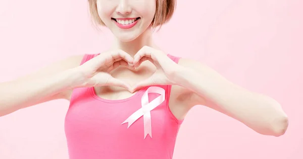 妇女显示心脏对您和穿粉红色丝带与预防乳腺癌概念 — 图库照片