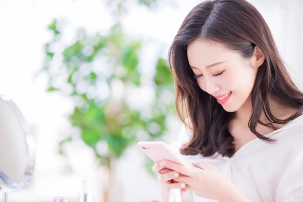 美しさの女性使用スマート フォン自宅 — ストック写真