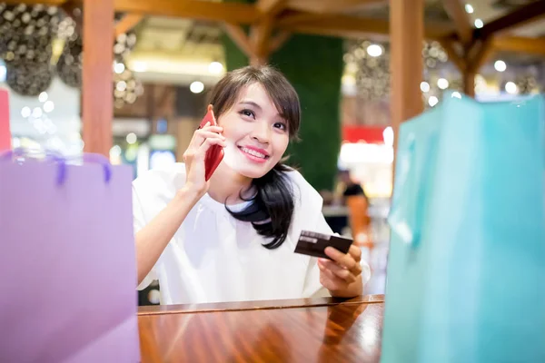 woman speak phone happily with her shopping bag and credit card in the restaurant