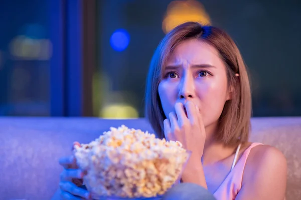 Young woman watch horror movies with popcorn at night