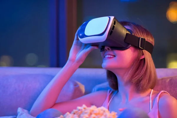 Young woman wear VR headset and watch movie with popcorn at night