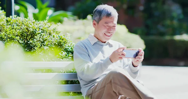 Old Man Watch Video Play Mobile Game Smarphone Happily Outdoor — стоковое фото