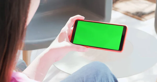 woman watch video by cell phone with green screen in the cafe