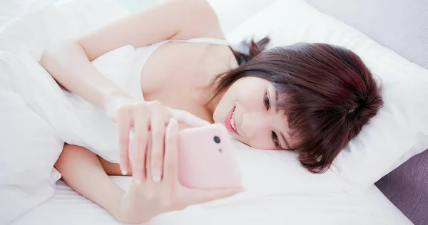 Kobieta używać telefonu w łóżku — Zdjęcie stockowe