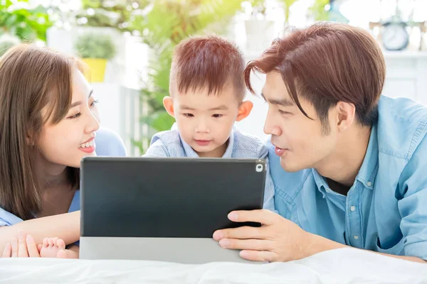 Родители играют с ребенком за планшетом — стоковое фото