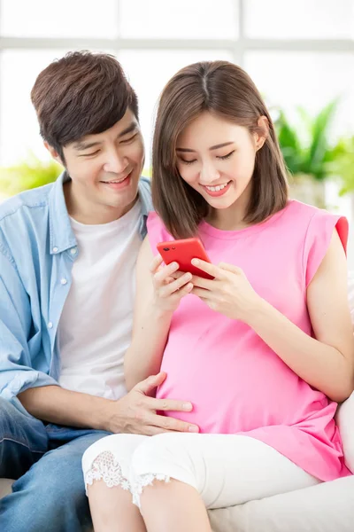 Pregnant couple use smart phone — Stock Photo, Image