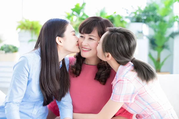 Duas filhas beijam a mãe em casa — Fotografia de Stock