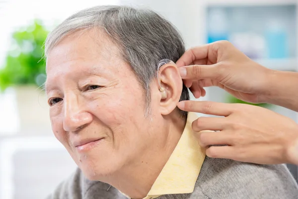 Arzt hilft Patient beim Tragen von Hörgerät — Stockfoto