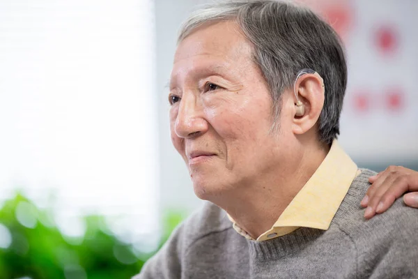 Arzt hilft Patient beim Tragen von Hörgerät — Stockfoto