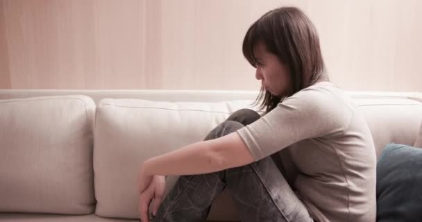 Mujer se siente deprimida en el sofá — Vídeos de Stock