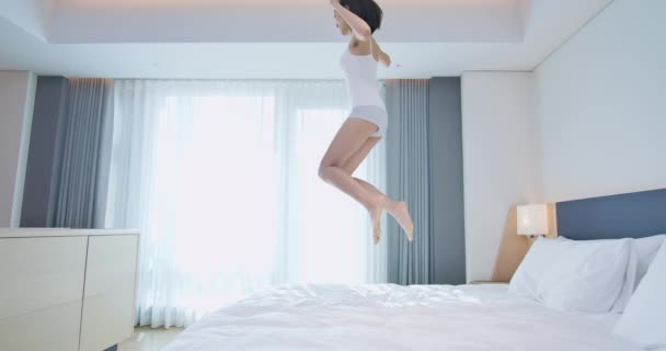 Молодая женщина прыгает на кровать — стоковое видео