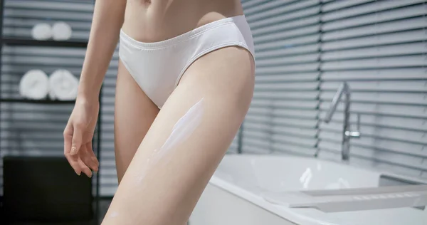 Donna che applica la crema sulla gamba — Foto Stock