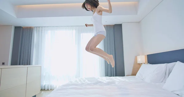 Молодая женщина прыгает на кровать — стоковое фото