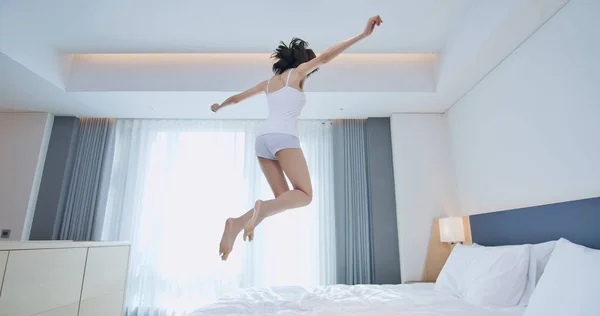 Ung kvinna hoppar på sängen — Stockfoto