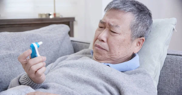 Азиатский пожилой человек использовать термометр — стоковое фото