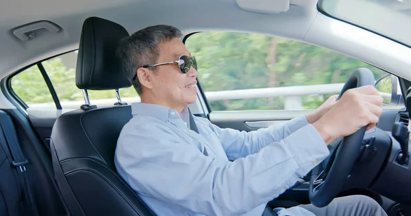 Aasialainen iäkäs mies ajaa autoa — kuvapankkivalokuva