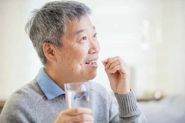 Alter asiatischer Mann nimmt Medizin — Stockfoto
