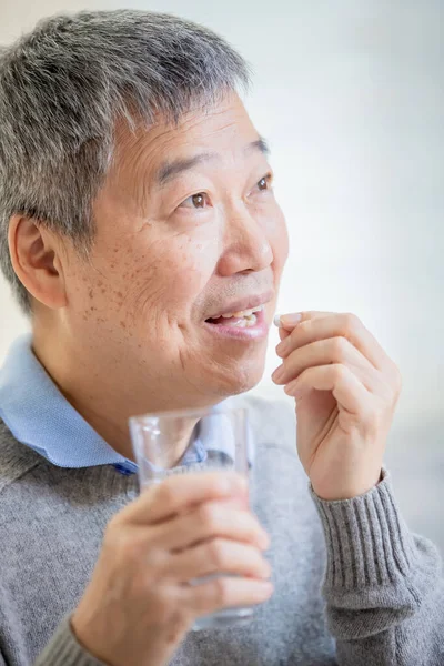 Alter asiatischer Mann nimmt Medizin — Stockfoto