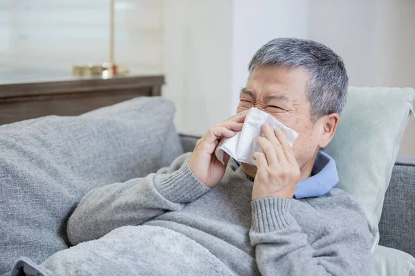 Азиатский пожилой больной человек чихает — стоковое фото