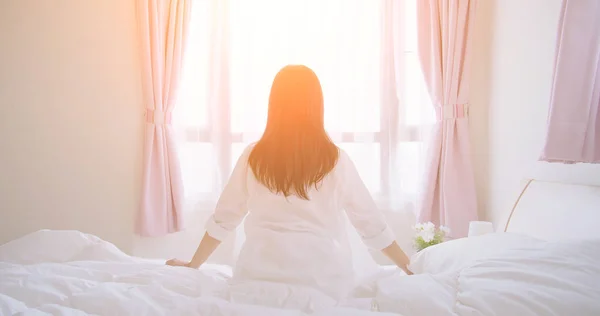 Азиатка сидит на кровати — стоковое фото