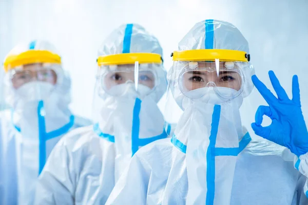 健康労働者は をジェスチャーであなたを見て 彼らは コロナウイルスの拡散を防ぐために 制御領域内の隔離ガウンや保護スーツや外科的フェイスマスクを着用します — ストック写真
