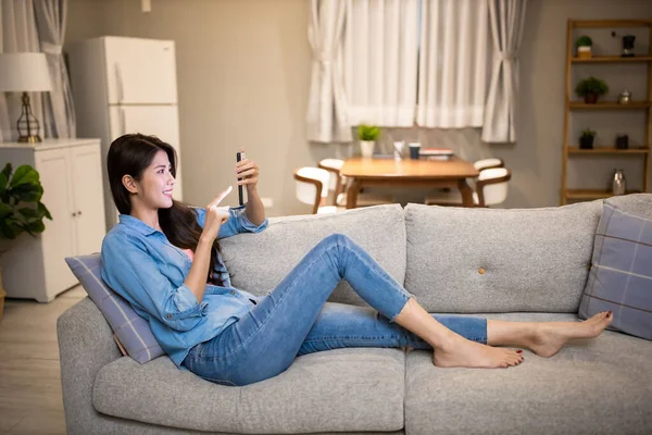 Aasialainen Nuori Nainen Käyttää Älypuhelinta Makaa Sohvalla Rauhassa Olohuoneessa Kotona — kuvapankkivalokuva