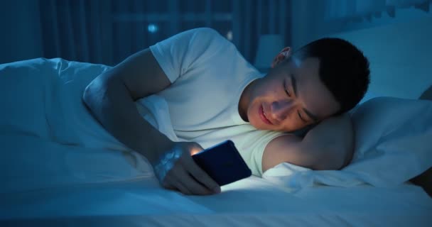 Мужчина пользуется смартфоном на кровати — стоковое видео