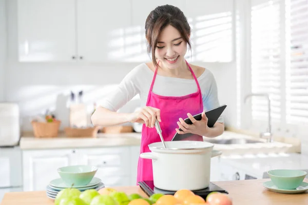 亚洲漂亮的家庭主妇用平板电脑找菜谱 在家做饭 — 图库照片