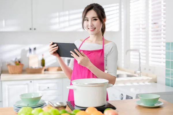 亚洲漂亮的家庭主妇用平板电脑找菜谱 在家做饭 — 图库照片